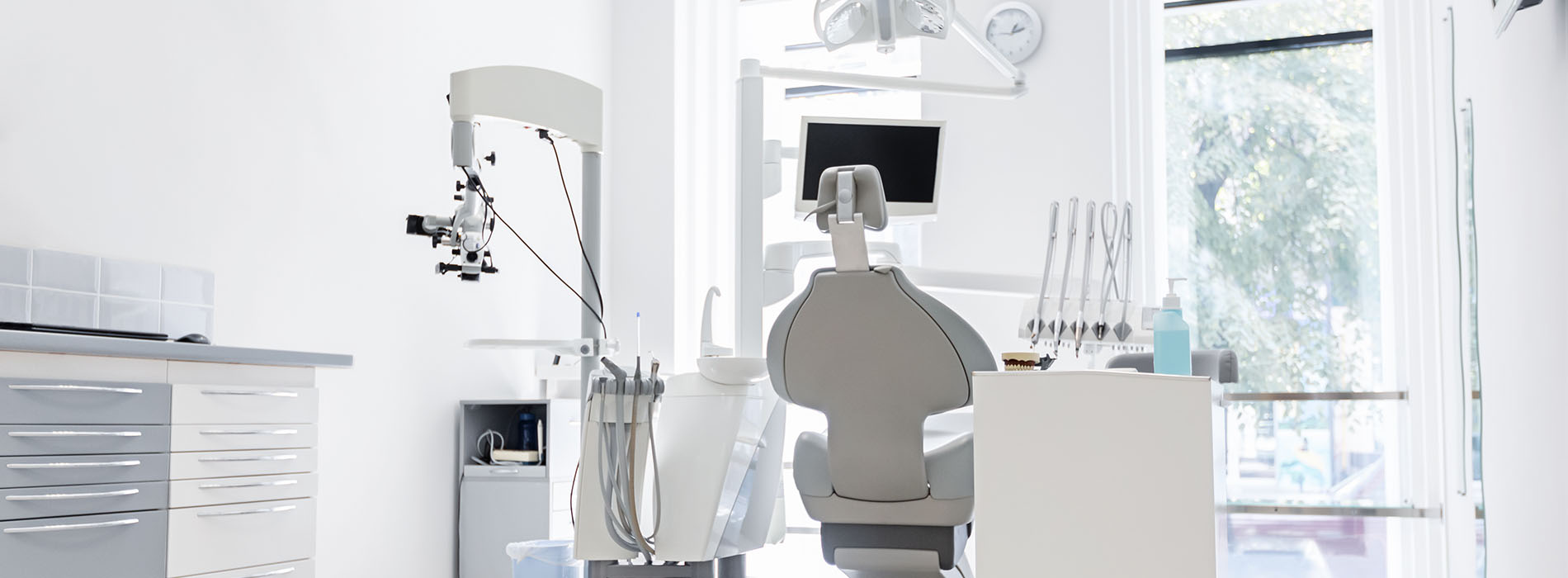 The image shows a modern dental office interior with a large window allowing natural light to enter.