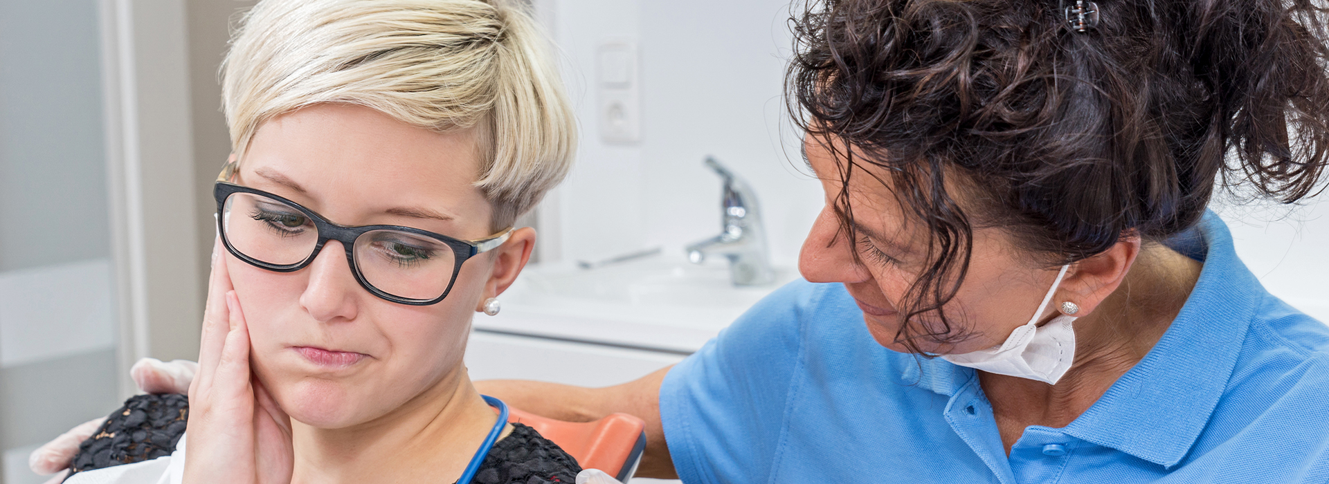 A photograph of a person receiving dental care from a professional in a clinical setting, with both individuals wearing protective eyewear.