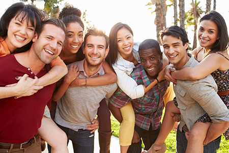 A group of young adults posing together for a photo outdoors during daylight with smiles on their faces.